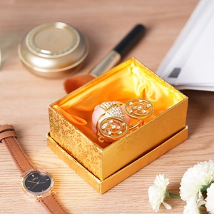Golden jewelry gift box with a diamond carriage figurine on a wooden tabletop
