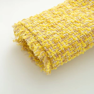 Detailed macro shot of yellow tweed fabric texture with delicate fringe edge finish