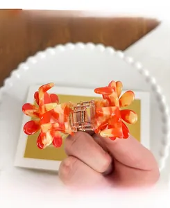 Détail de la pince à cheveux en acétate marbré orange avec ressort métallique robuste