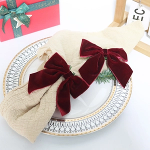 Detail of red velvet bow with green pine needles on a festive dinner plate setting
