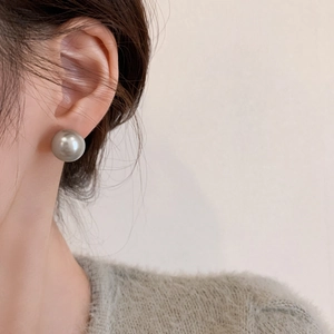 Close-up of a large grey pearl stud earring worn on model for a minimalist style