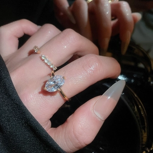 Macro shot of gold zircon oval ring and pavé band set on finger against dark background