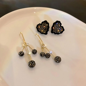 Détail de boucles d'oreilles cœur noir et pendants à trois boules plaqués or luxe