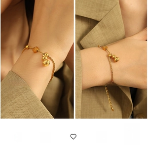 Detail of gold gourd pendants and Fu character charm on woven steel bracelet