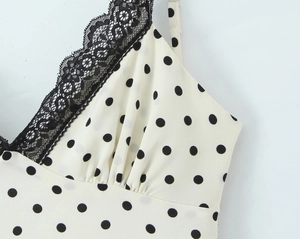 Dettaglio del bordo in pizzo nero e del motivo a pois su una canotta con scollo a V