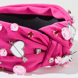 Detail of rose pink knotted headband with heart arrow accents and rhinestones