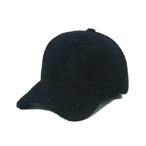 Detailed view of black knitted baseball cap with shimmering lurex and wool texture