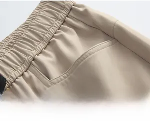 Dettaglio vita elastica e tasca obliqua su pantaloni cargo beige con trama tessile