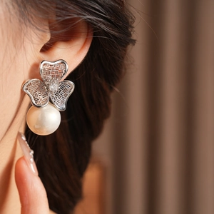 Detailed close-up of a vintage silver flower earring with pearl on a model's ear