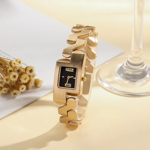 Detail view of gold bangle watch with brushed metal finish and rectangular black dial