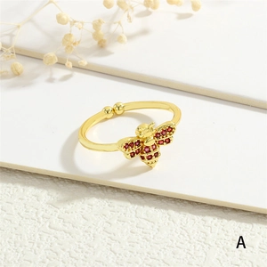 Macro shot of 18k gold plated bee ring with red zircon wings on a textured surface