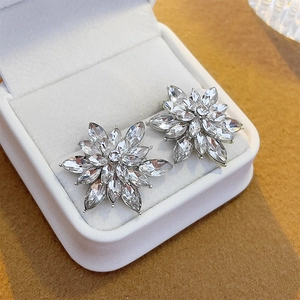 Macro shot of silver-colored flower stud earrings with zircon stones in a jewelry box