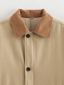 Detail of khaki jacket with brown corduroy collar and black buttons on textured fabric