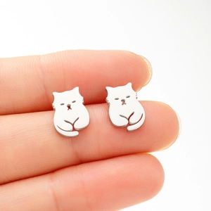 Makroaufnahme von minimalistischen Katzen-Ohrsteckern aus Edelstahl auf einem Finger