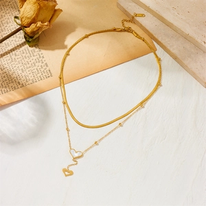 Double-layered golden titanium necklace with heart pendants on vintage floral background
