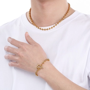 Détail d'un collier en perles dorées et d'un bracelet avec fermoir OT en cœur sur modèle