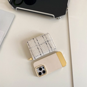 Classic black and white tweed zip wallet with gold zipper on a minimalist desk