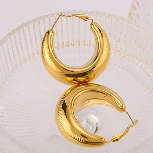 Polished hollow gold hoop earrings made of stainless steel displayed on a glass tray