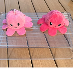 Detail of reversible octopus plush with happy and angry expressions and metal keychain hooks