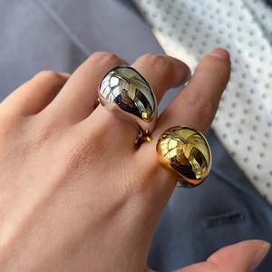 Detail of chunky polished gold and silver water drop rings on model hand