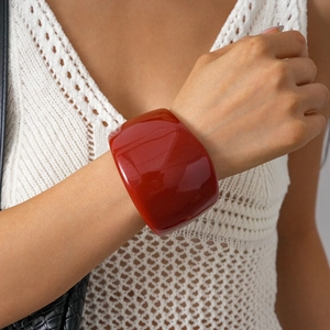 Close-up of a wide red resin geometric bangle on a model wrist for a bold summer look