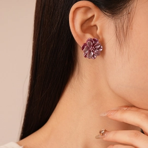 Gros plan d'élégantes boucles d'oreilles fleurs en résine mauve portées par un mannequin