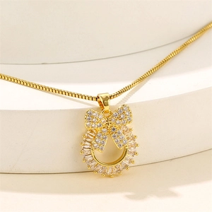 Gold stainless steel bow necklace with sparkling crystals on a minimalist display