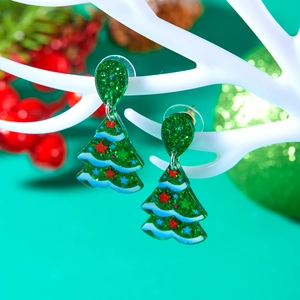 Close-up of festive green acrylic Christmas tree earrings with colorful star patterns