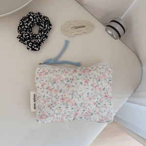 Detail of floral quilted cotton pouch with 'Simple Wish' label and blue cord zipper pull