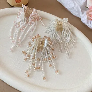 Three elegant pearl tassel hair clips in white, pink, and champagne on a decorative tray