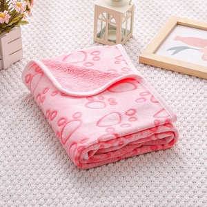 Detail of pink flannel pet blanket with red paw prints folded on a soft white knit base