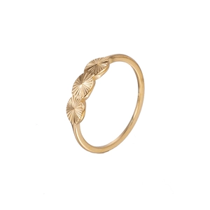 Detail of golden ring with three radial textured circular motifs on a slim metallic band