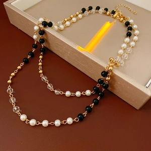Détail d'un collier double épaisseur avec perles, billes noires et fermoir doré réglable