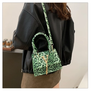 Dettaglio borsa a mano leopardata verde brillante con logo V dorato e nappina decorativa