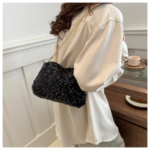 Detail of a sparkling black sequin crossbody bag with an elegant gold chain strap