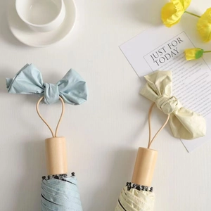 Sky blue and beige folding umbrellas with wooden handles and bow straps in a flat lay