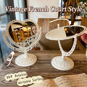 Vintage heart-shaped swivel vanity mirror with ornate French baroque carvings on desk