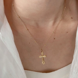Minimalist gold stainless steel cross pendant necklace on beaded chain worn by model