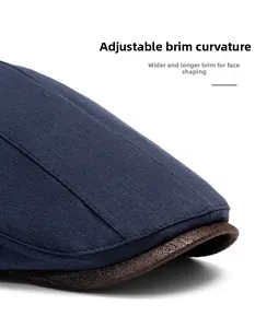 Detail of blue cotton beret with brown leather brim showing flexible folding brim feature