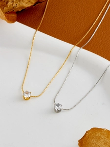 Detail of silver and gold snake chains with classic four-claw zircon pendants
