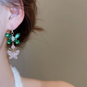 Close-up of elegant butterfly earrings with green and clear crystals on a model
