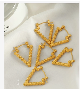 Detail of geometric gold triangle beaded earrings on elegant white satin fabric