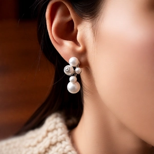 Detailed view of silver needle pearl earrings with crystals worn by a model