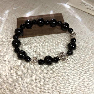 Gros plan d'un bracelet en perles noires avec pendentif croix argentée sur bois
