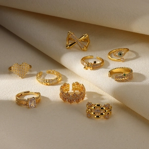 Golden minimalist rings collection with heart and zircon accents on beige fabric