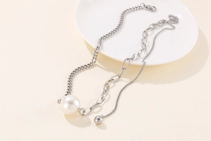 Detail of silver titanium necklace with white pearl pendant and asymmetric mixed chain style