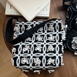 Close-up of butterfly embroidery and 3D floral details on black and white canvas bag