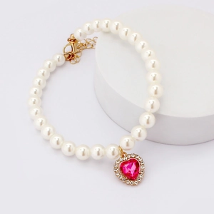 Close-up of pearl pet necklace with pink heart gemstone pendant and rhinestone edge