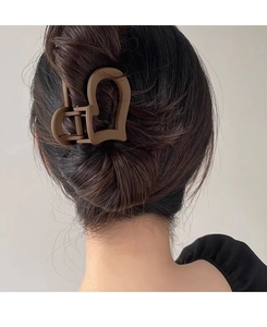 Close-up of matte brown heart-shaped hair claw clip worn on model hair from back view
