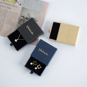 Detail of sliding jewelry boxes in navy and black with gold logo and soft flocking